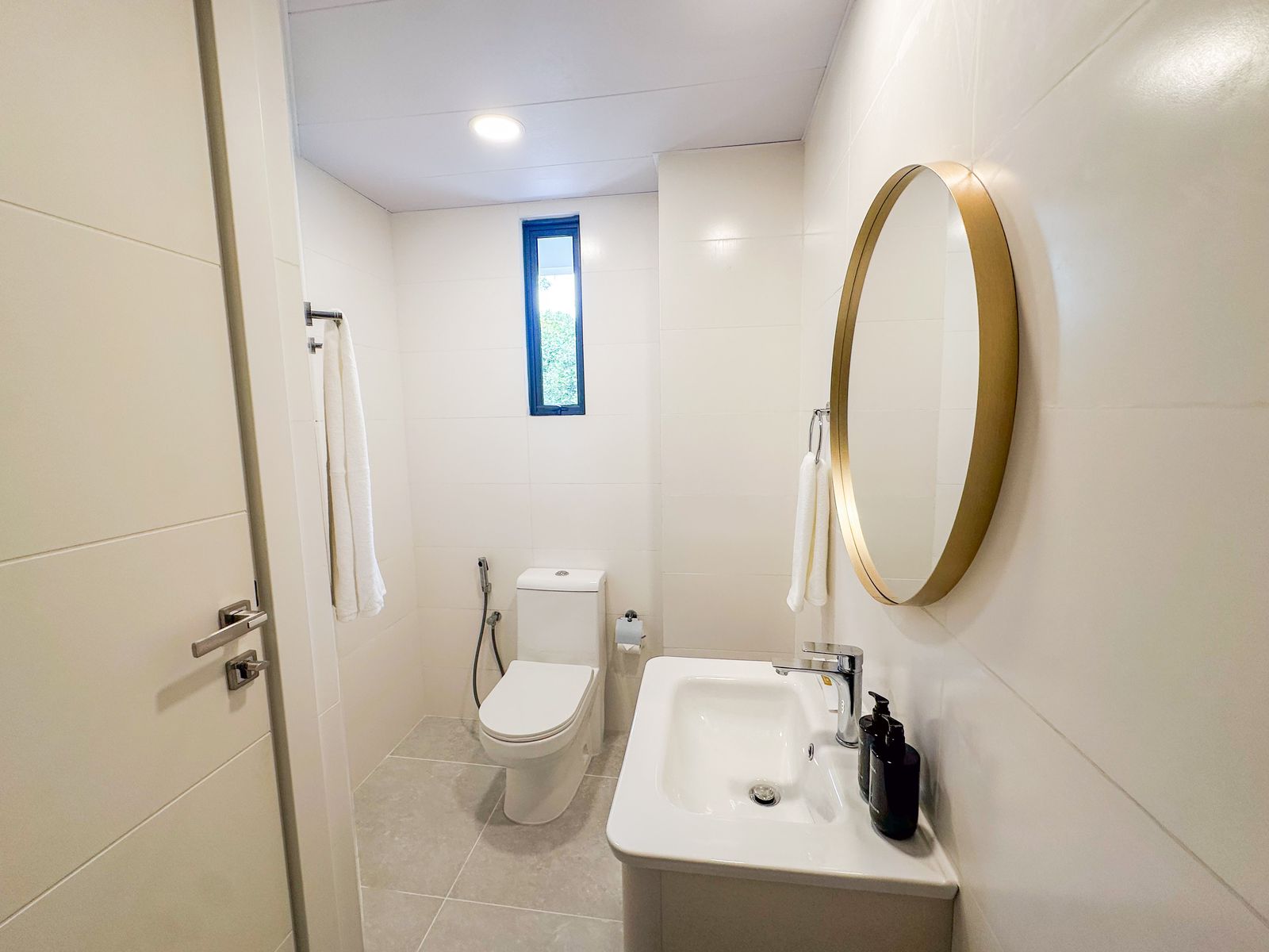 Bright en-suite with round gold mirror and slim window