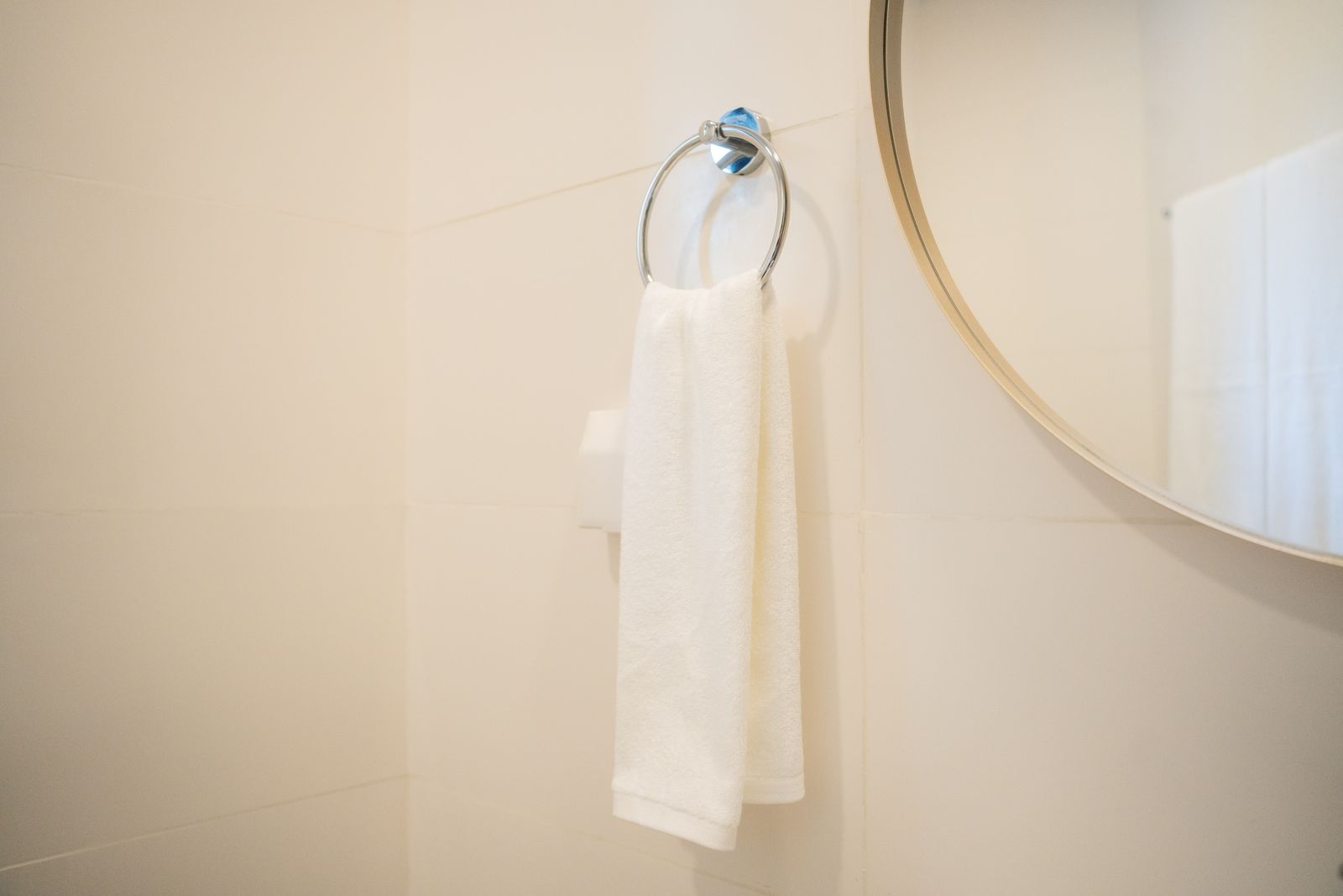 Fresh white towels on a chrome ring beside the round mirror