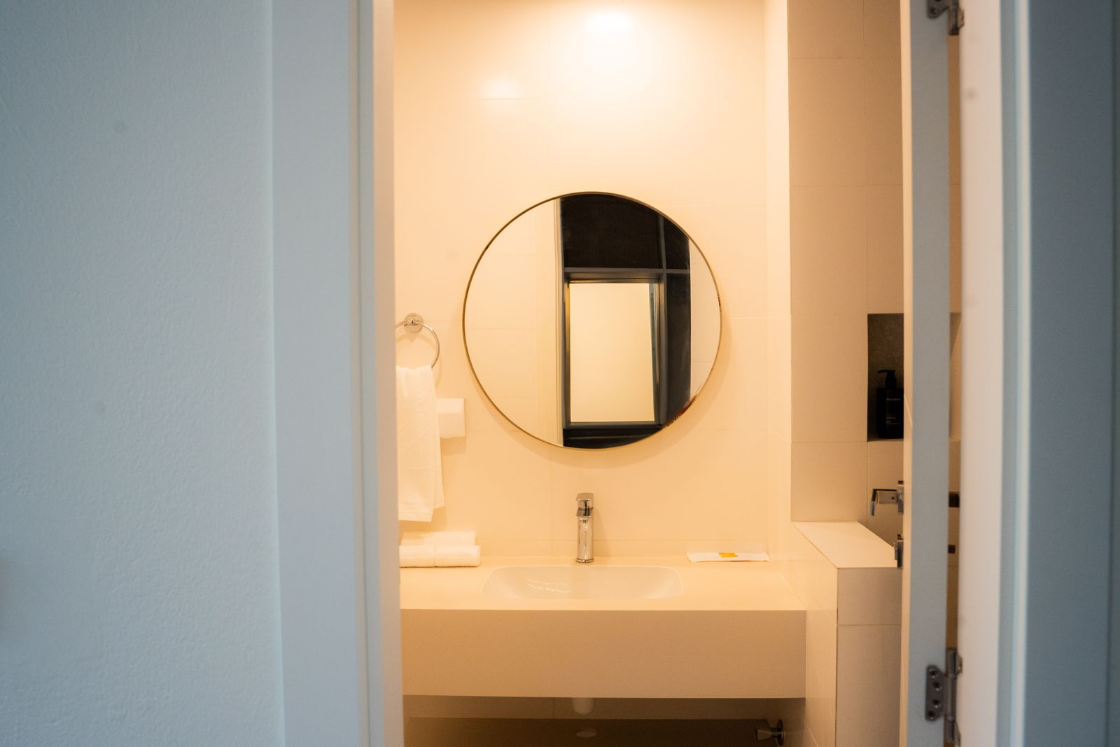 En-suite vanity with round mirror and stone counter