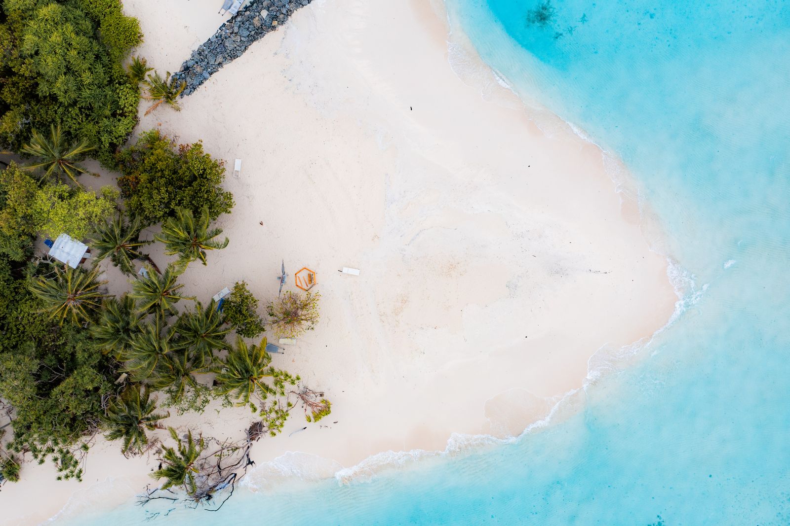 Beach loungers and palm shade seen from overhead