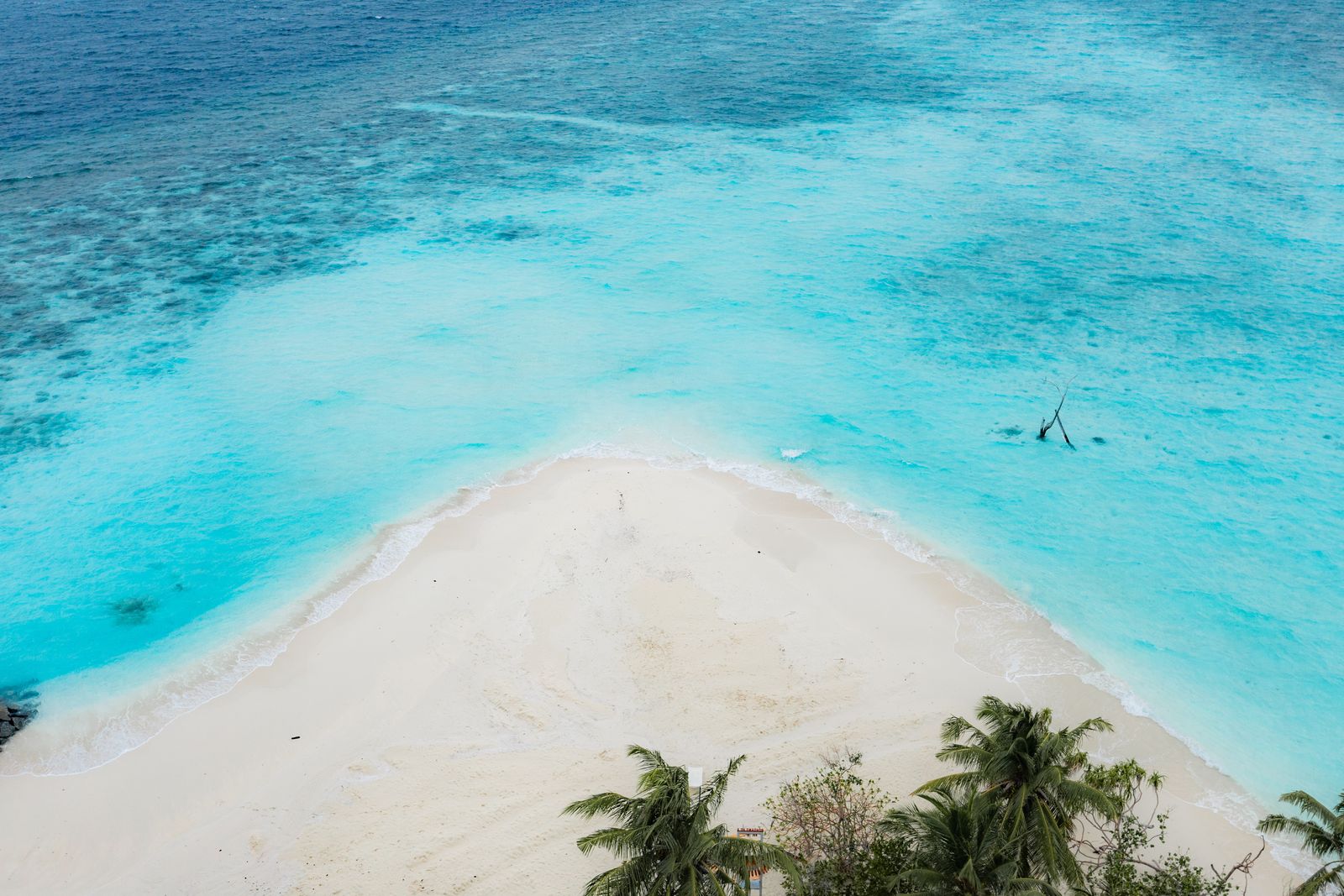The beach point from directly above, sand meeting clear shallows