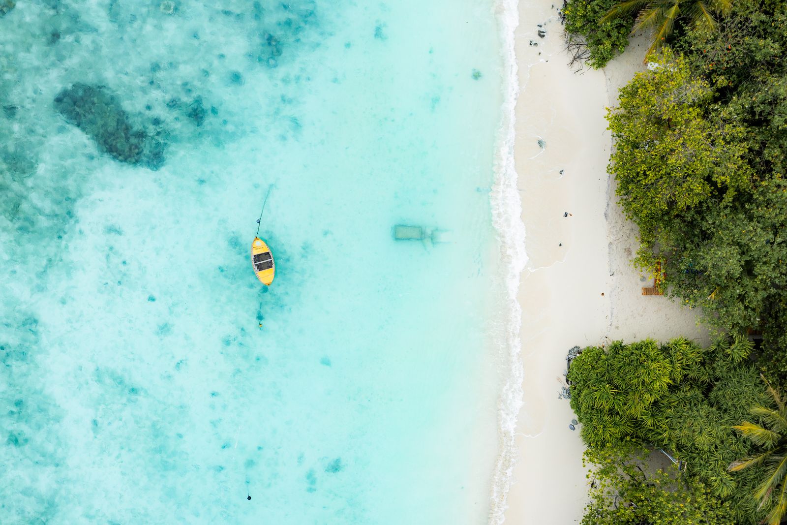 Yellow dhoni moored in the shallow lagoon, seen from above