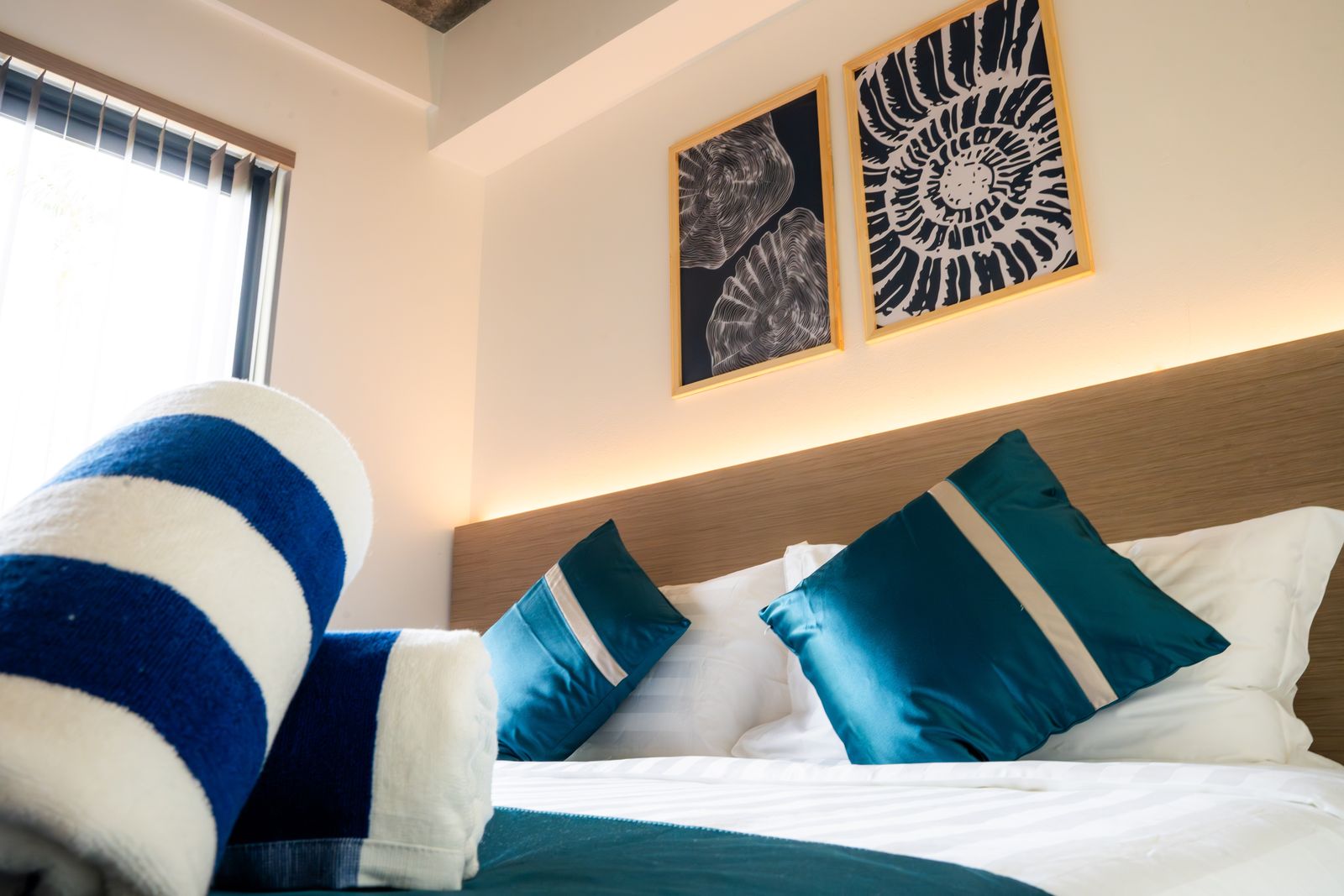 Bed detail with shell artwork and warm headboard lighting